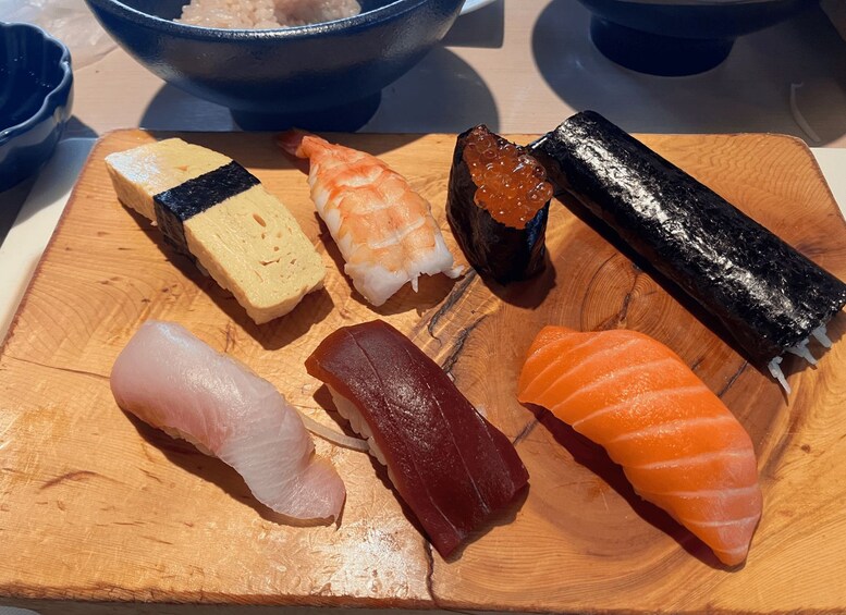 A wooden cutting board with various types of sushi. 2