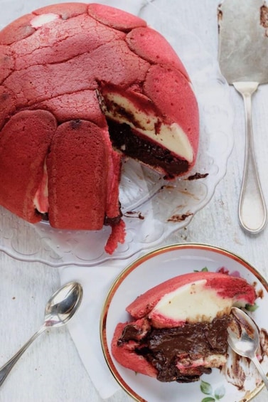 A red velvet cake with a slice cut out, placed on a white plate with a spoon beside it. 2