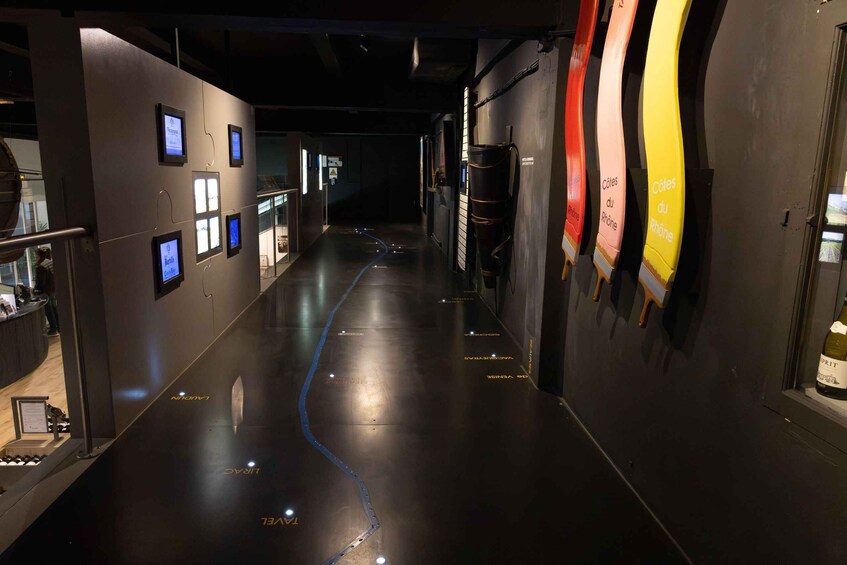 A dimly lit corridor with a reflective floor, displaying signs and labels on the walls, and a bottle of wine on the right. 5
