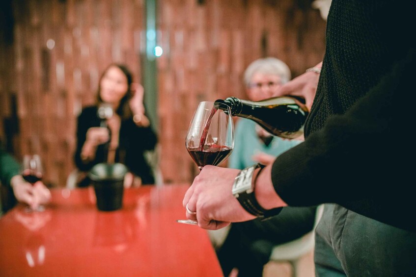 A person pouring red wine into a glass. 4