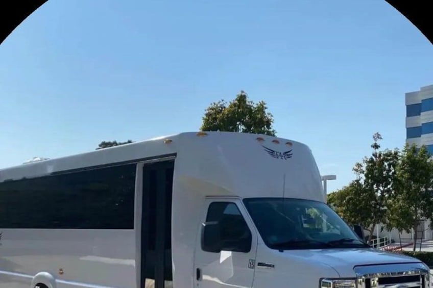 A white RV parked outdoors with a clear sky. 1