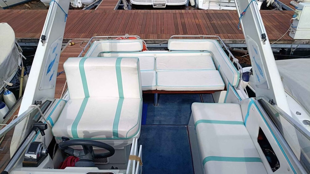 A boat's interior with seating, a steering wheel, and a blue floor. 2