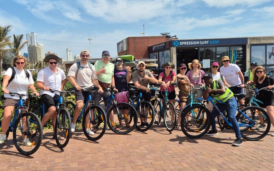 A group of people on bicycles in front of a surf shop. 1