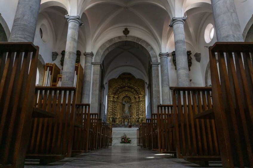 An interior of a church with high arched ceilings, wooden pews, and a central altar with ornate decorations. 5