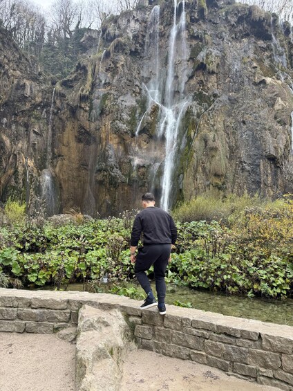 A person standing on a stone wall overlooking a waterfall. 2