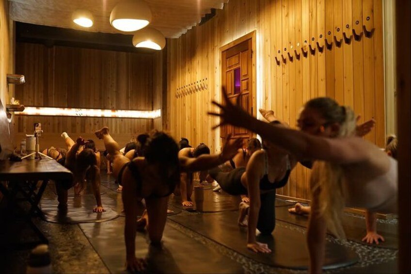 A group of people in a wooden room performing yoga. 3