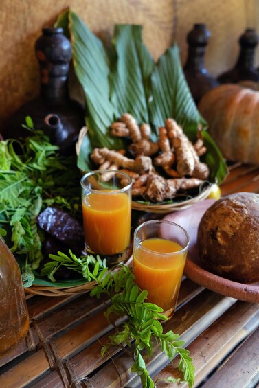 A table with a glass of orange juice, a loaf of bread, and various fruits and vegetables. 2