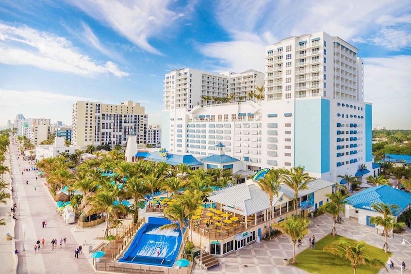 A resort with multiple buildings, palm trees, and a swimming pool. 5