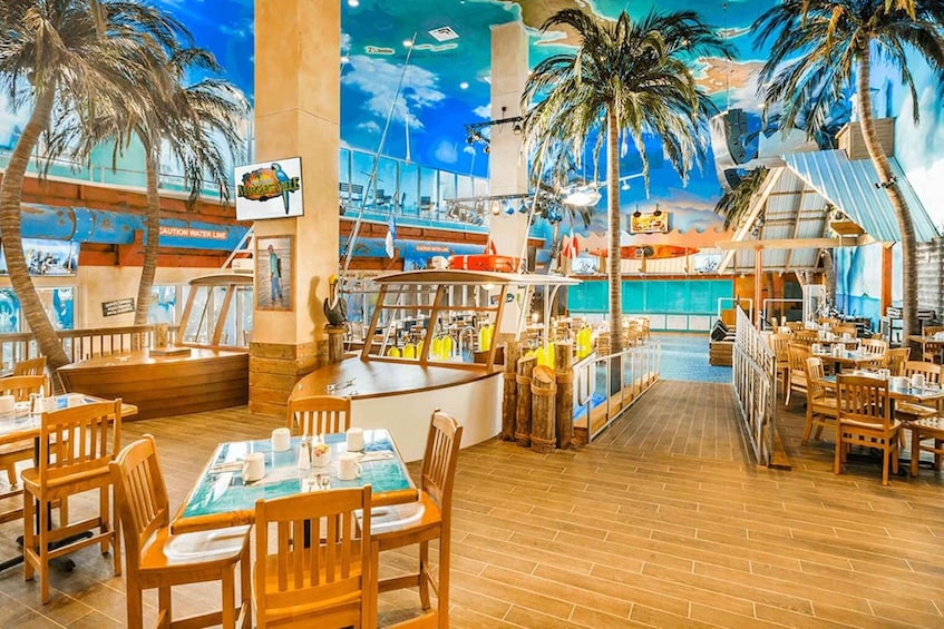 A restaurant with wooden tables and chairs, a mural of a tropical scene, and a pool area. 4