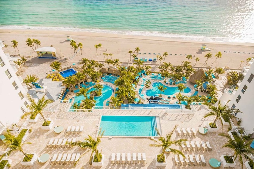 A resort with multiple swimming pools, palm trees, and a beach. 2