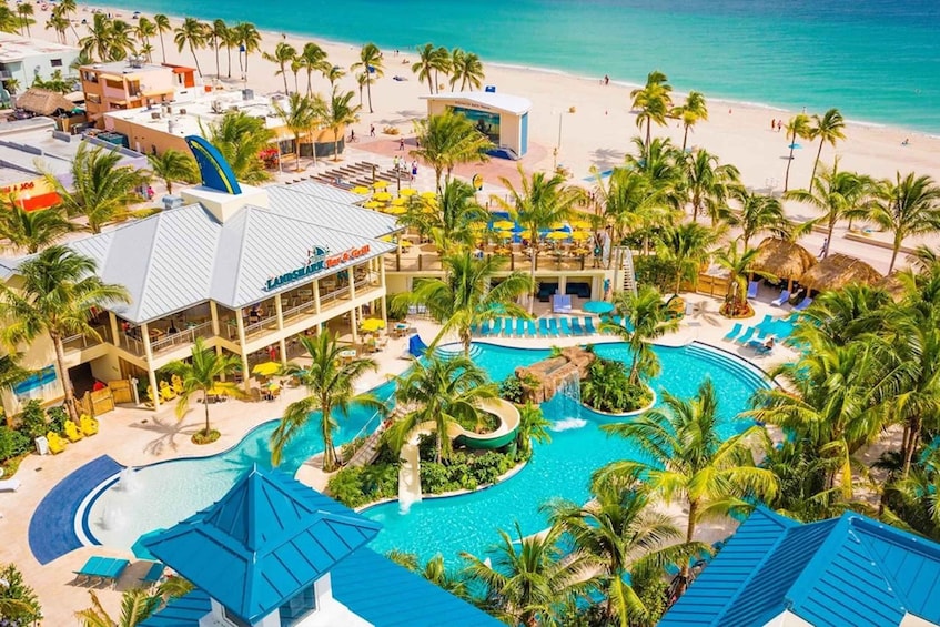 A resort with a swimming pool, palm trees, and a beach. 1