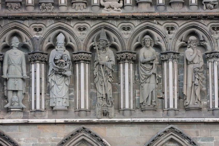 A stone facade with Gothic arches and statues of religious figures. 5