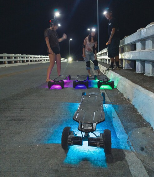 A nighttime scene with people on hoverboards and a skateboard on a bridge. 3