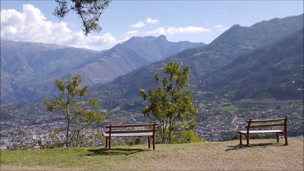 Two wooden benches overlooking a valley with mountains in the background. 3