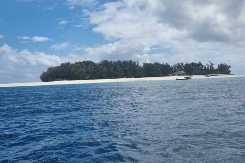 A clear blue sea, a sandy beach, and a small island with dense vegetation. 5