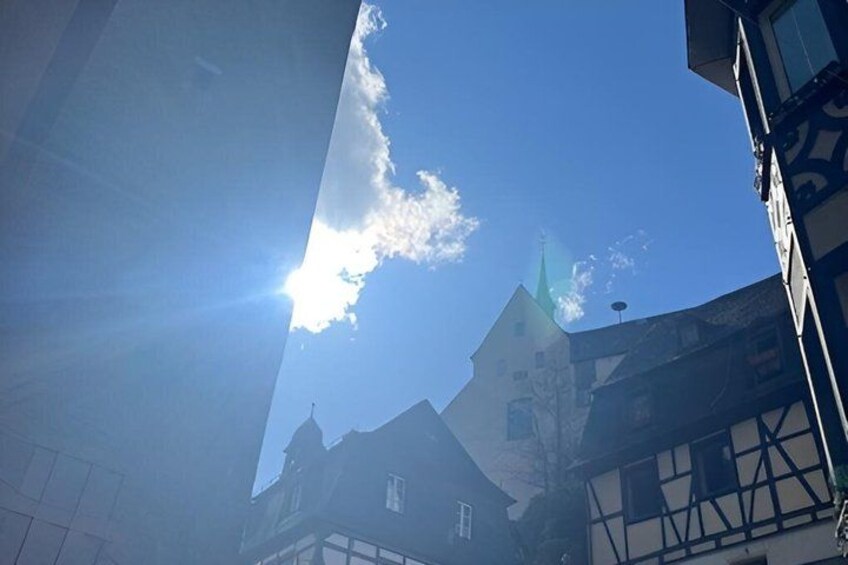 A clear sky with the sun shining, a church with a green spire, and traditional half-timbered buildings. 5