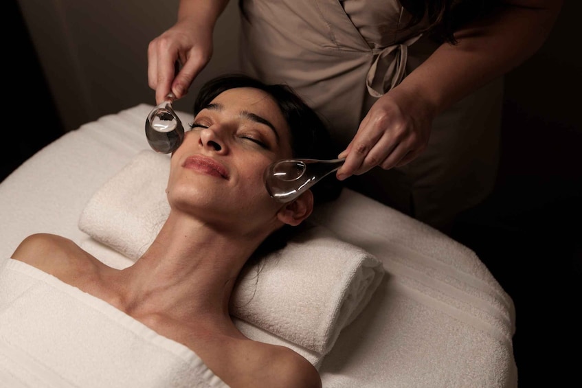 A person lying on a treatment table receiving a facial treatment. 5