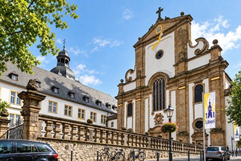 A historic church with a bell tower, a stone bridge, and a street with cars and bicycles. 5