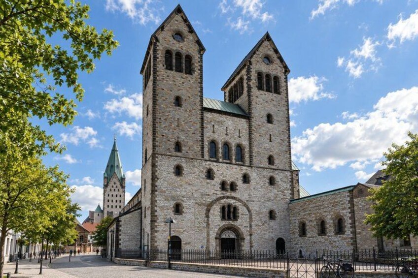 A historic stone church with two towers and a green spire. 4