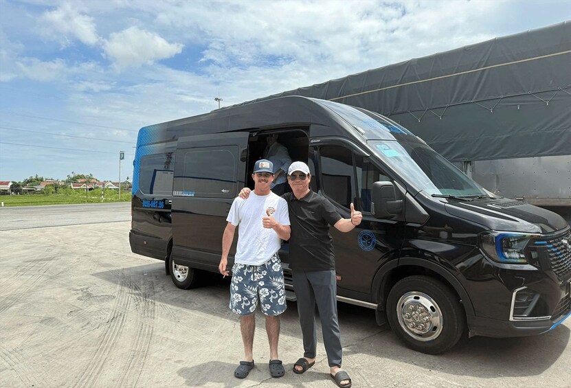 Two people standing next to a black van with a partially open door. 3
