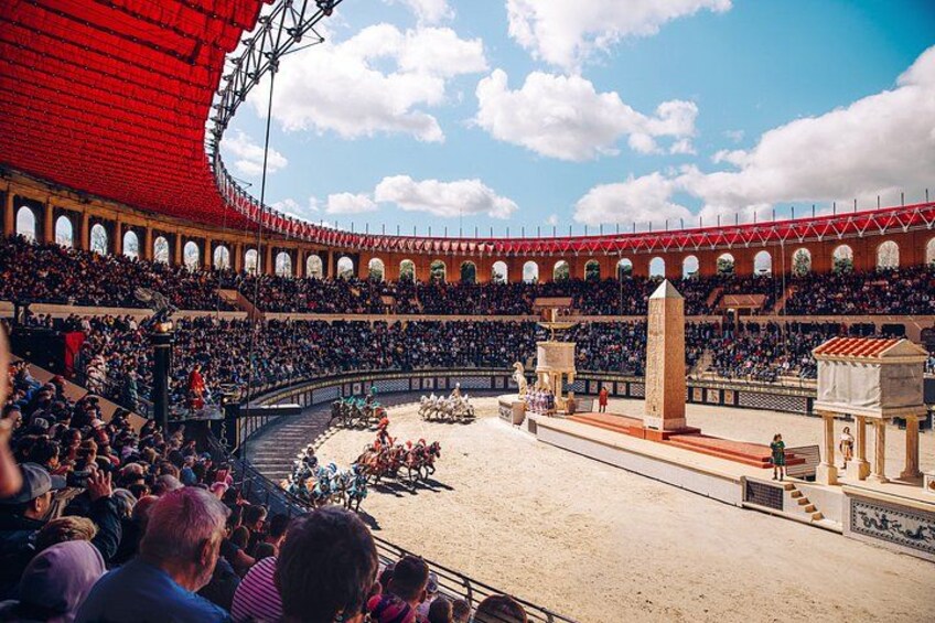 A large outdoor amphitheater with tiered seating and a central stage. 5