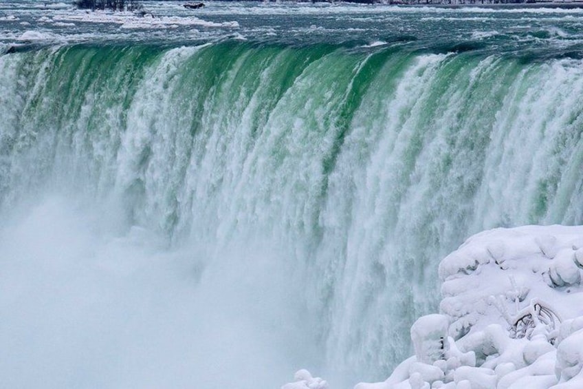 A powerful waterfall with snow-covered rocks at the base. 5