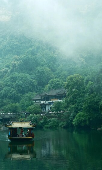 A traditional boat on a calm river, surrounded by lush greenery and a misty forested hillside. 4