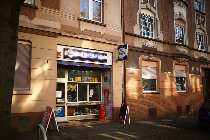 A storefront with a sign reading 'TRINKHALLE' and 'Kronen' beer brand. 2