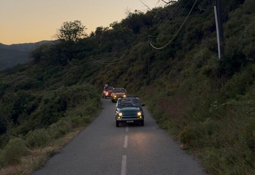 A road with vehicles driving on it, surrounded by hills and vegetation. 1