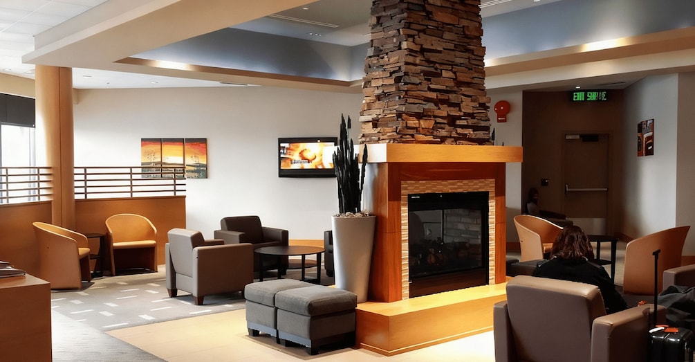 A modern lounge area with a stone fireplace, comfortable seating, and a television screen. 1