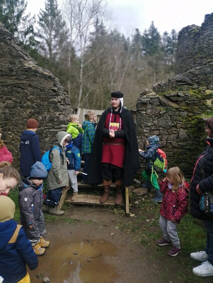 A person in academic regalia standing on a stone platform surrounded by people. 3
