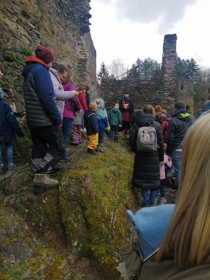 A group of people standing on a rocky path with a stone structure in the background. 2