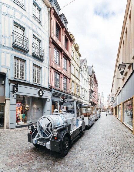 A cobblestone street lined with colorful historic buildings, a tram, and a vintage car. 4