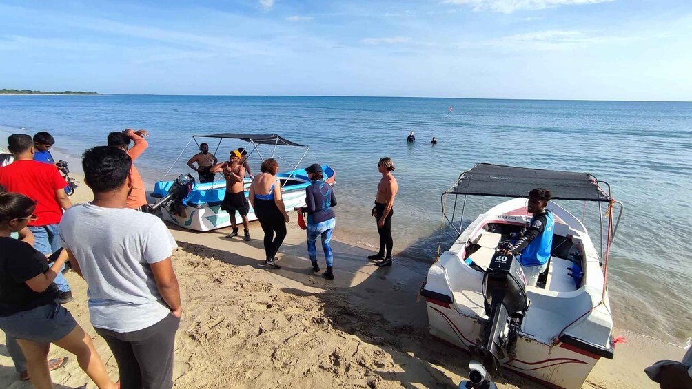 A group of people on a beach with boats and a calm sea in the background. 3