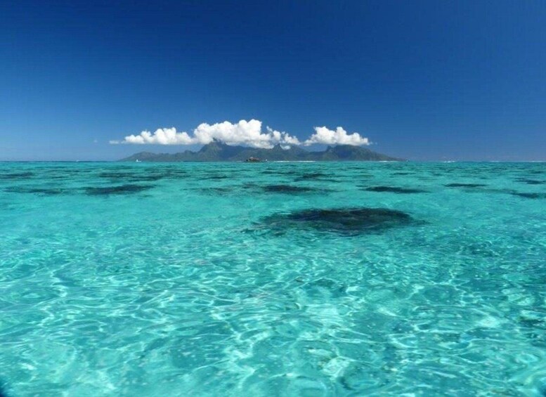 Un mare turchese trasparente con una piccola isola all'orizzonte. 1