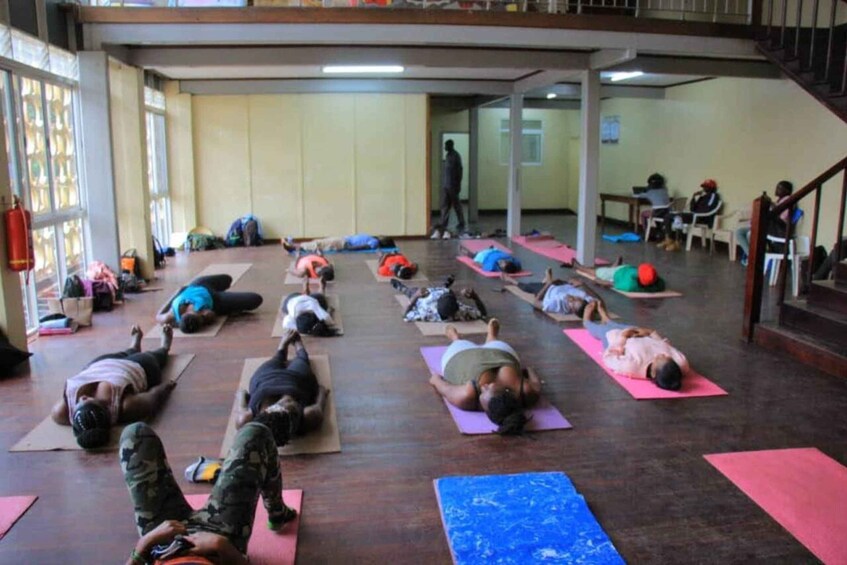 A group of people lying on mats in a room with wooden floors and large windows. 2