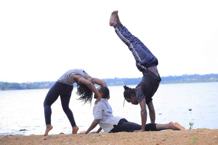 Three people performing acrobatics on a beach with a body of water in the background. 1