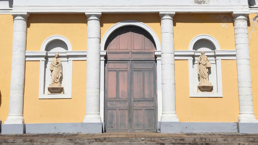 A building facade with a central arched door flanked by two statues in niches. 3