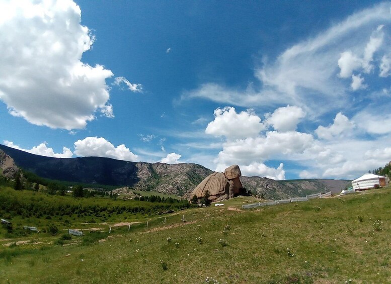 Un paisaje montañoso con una yurta blanca sobre una colina cubierta de hierba. 5