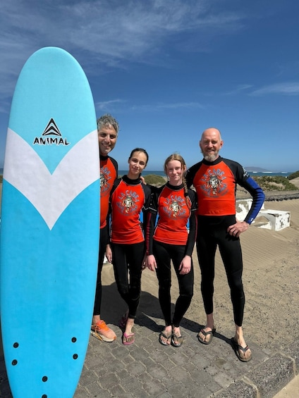 Quatre personnes se tiennent devant une planche de surf bleue sur laquelle est écrit le mot « ANIMAL ». 4