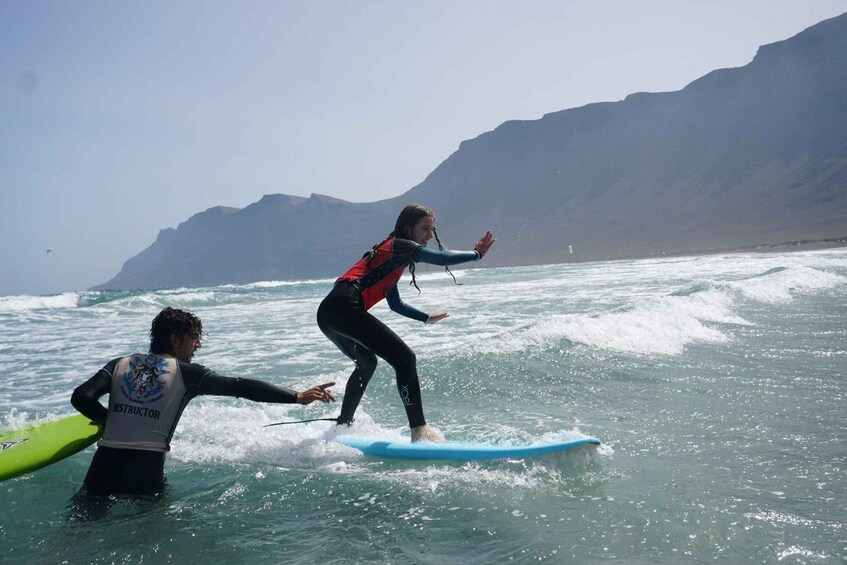 Une personne faisant de la planche à voile sur une vague, avec une côte montagneuse en arrière-plan. 2
