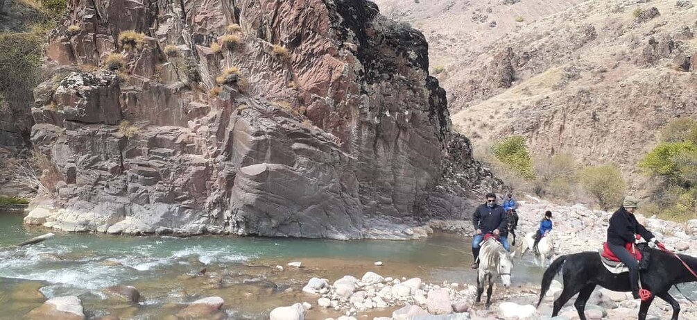 Un fiume che serpeggia attraverso un canyon roccioso, con persone a cavallo. 2