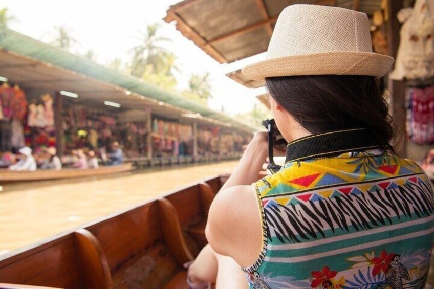 A person in a boat with a straw hat, wearing a colorful patterned shirt, looking at a market. 2
