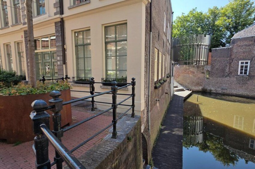 A canal with a brick walkway and a building with large windows. 4