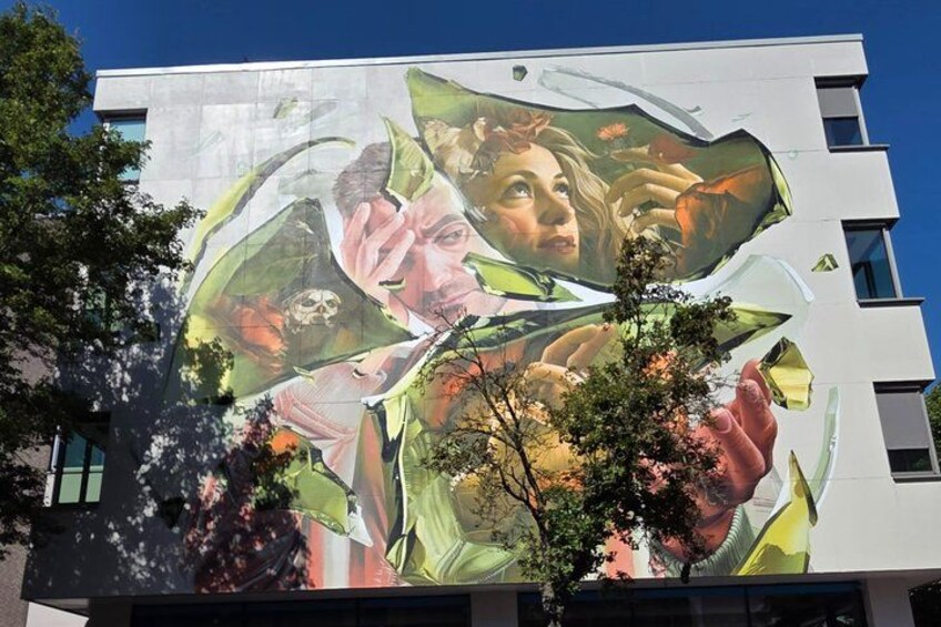 A building with a large mural featuring floral and human elements. 3
