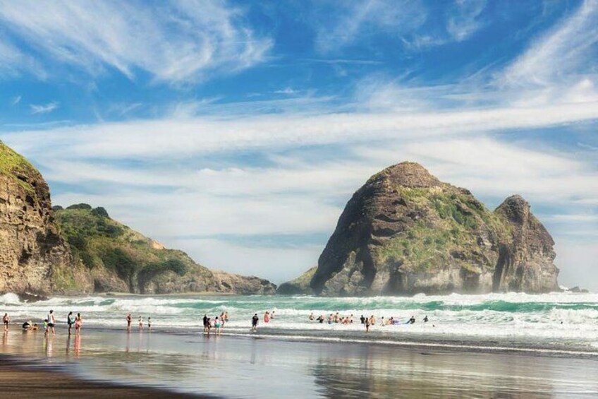 A beach with waves, people, and rocky cliffs. 1