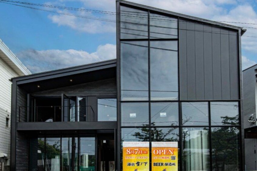A modern building with large windows and a sign advertising beer. 1