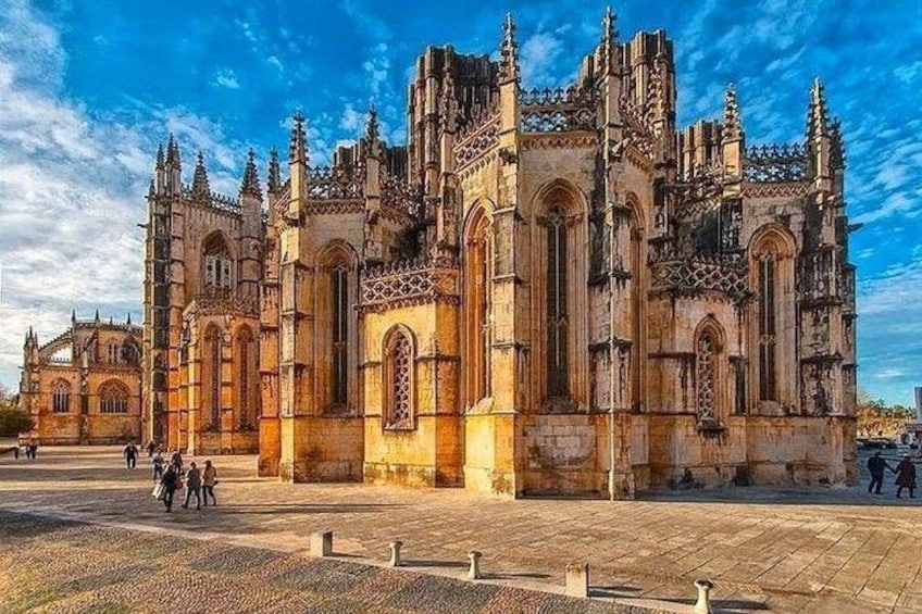 A historic cathedral with intricate architecture, a paved plaza, and a clear blue sky. 1