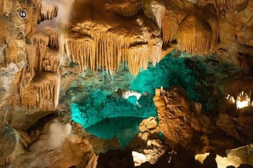 A cave with stalactites and stalagmites, a pool of water, and a cave number sign. 3