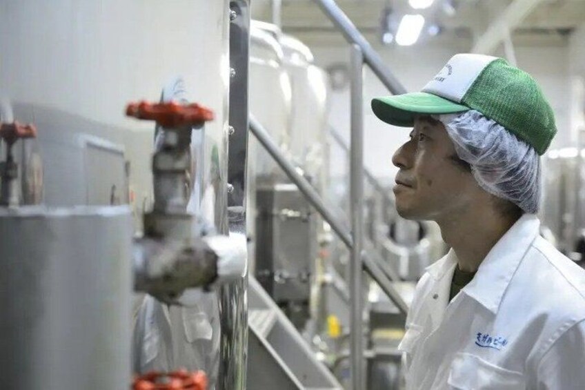 A person in a white lab coat and hairnet working with machinery in a clean, industrial setting. 4